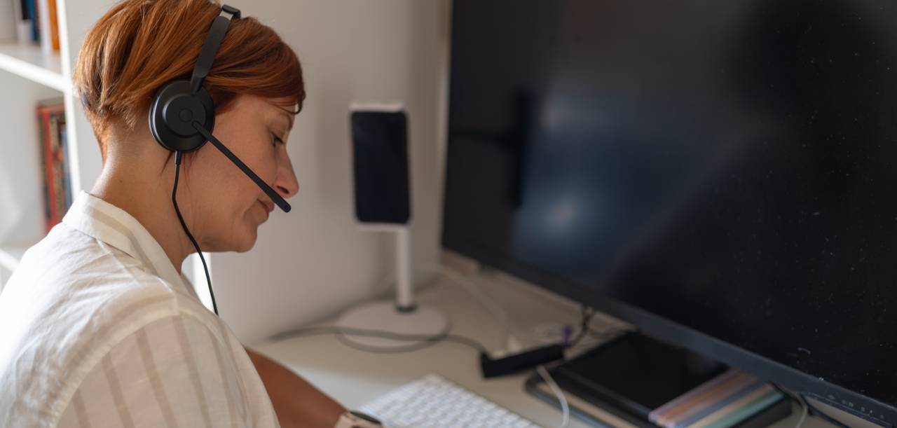 Interpreter wearing a headset during a remote simultaneous interpreting assignment at her home office desk