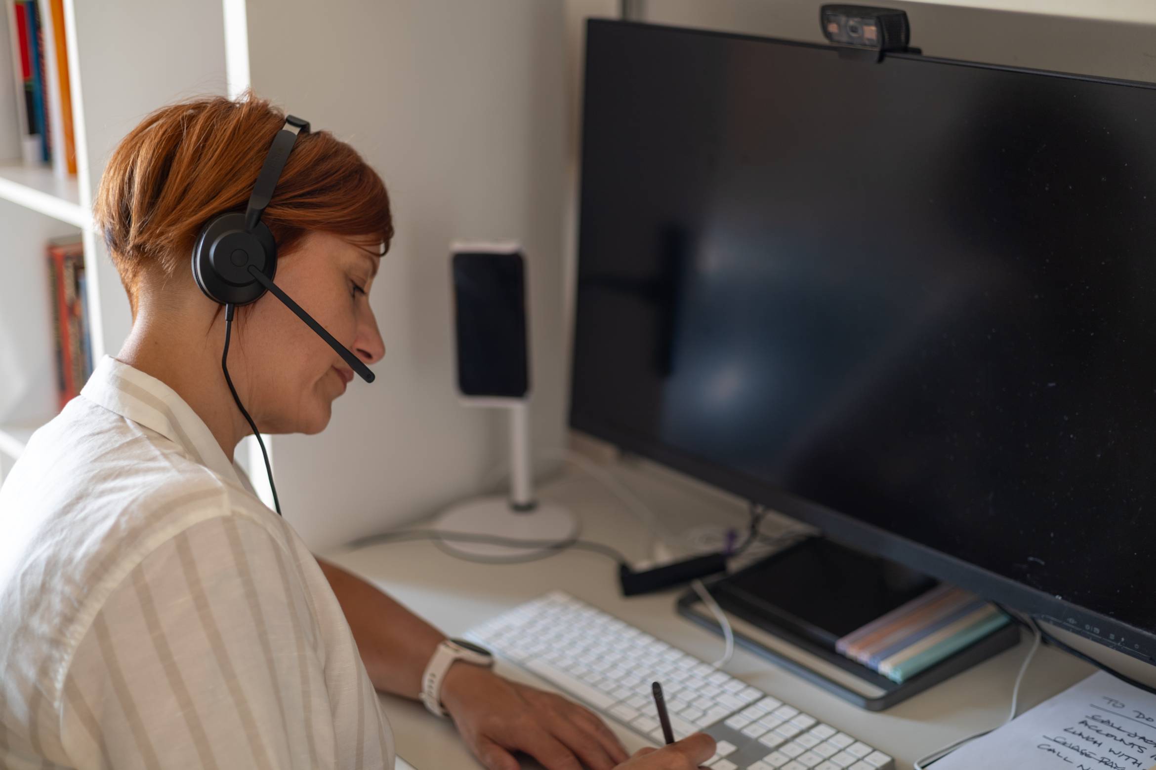 Interpreter wearing a headset during a remote simultaneous interpreting assignment at her home office desk