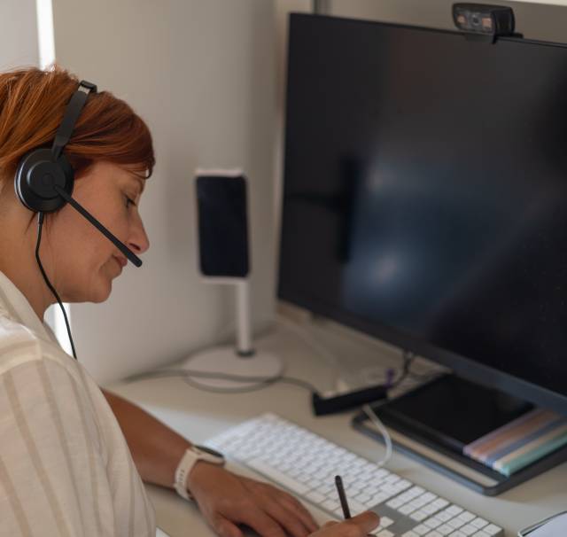 Interpreter wearing a headset during a remote simultaneous interpreting assignment at her home office desk