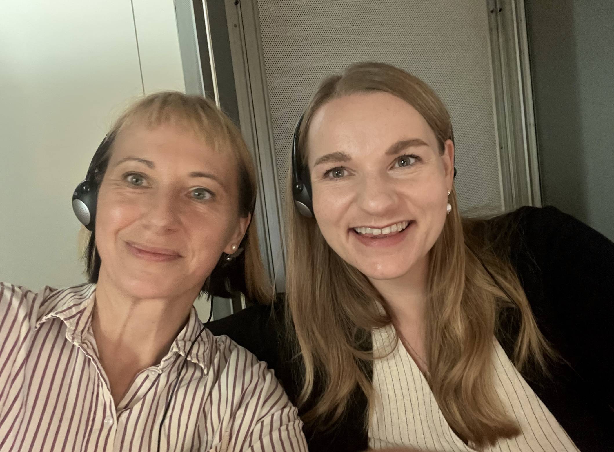 Two interpreters in the booth: the image shows two smiling women wearing headsets.