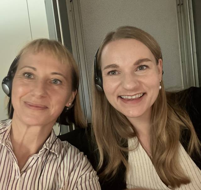 Two interpreters in the booth: the image shows an image of two smiling women wearing headsets.