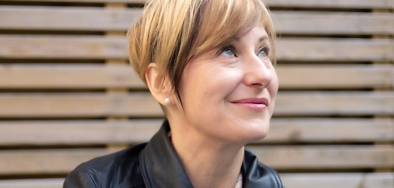 Professional conference interpreter looking to the side in a thoughtful pose against a wooden background.