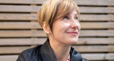 Professional conference interpreter looking to the side in a thoughtful pose against a wooden background.